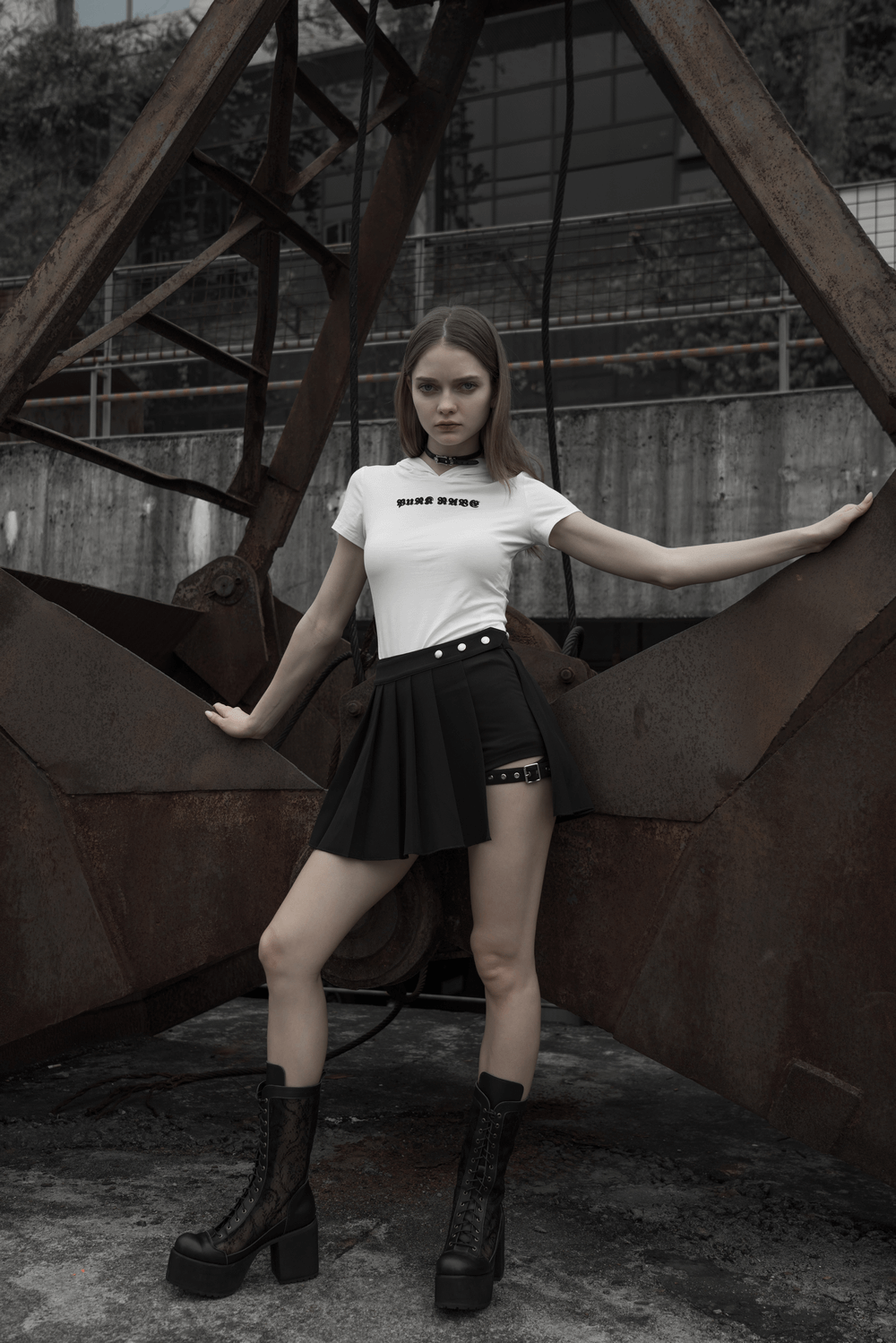 Gothic Punk model wearing a black plaid mini skirt and white tee against an industrial backdrop.