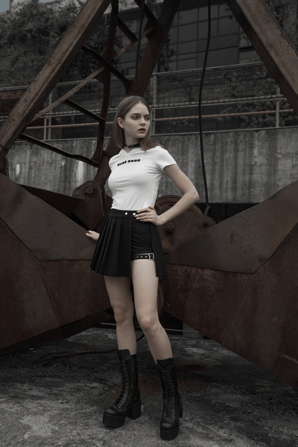 Model in Gothic Punk plaid mini skirt and graphic tee, showcasing edgy Harajuku style against industrial backdrop.