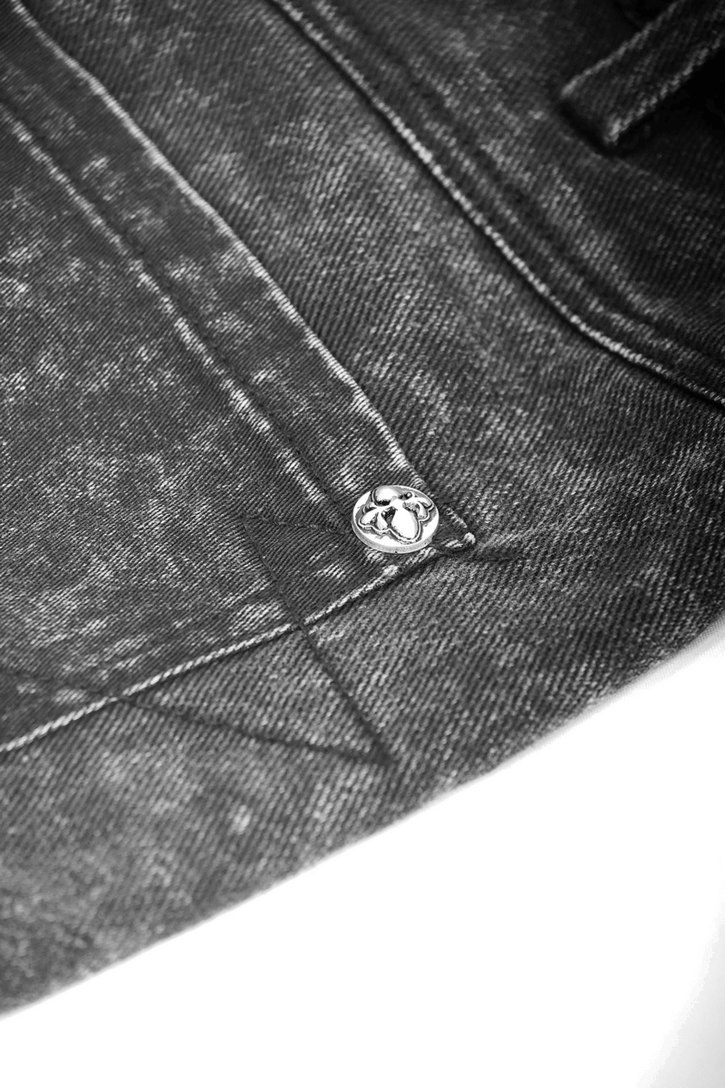 Close-up of a silver rivet on black denim fabric, highlighting punk fashion details.