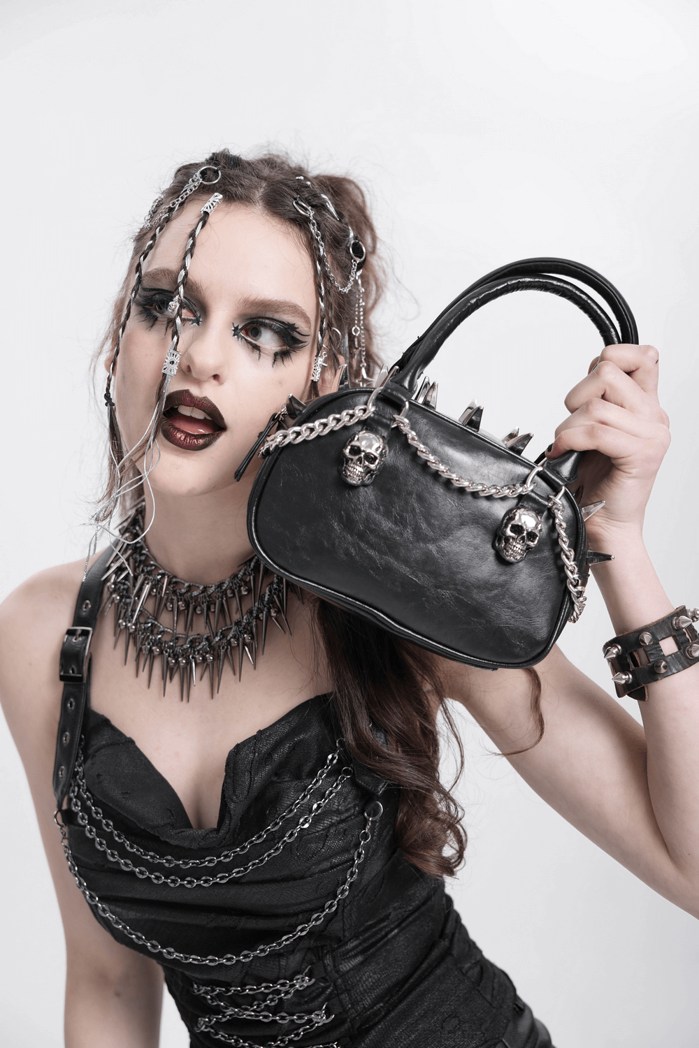 Gothic punk model showcasing a skull-studded handbag with spikes and chain strap, perfect for alternative fashion.