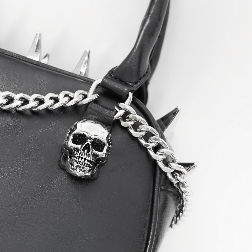 Close-up of a gothic punk handbag with spikes, silver skull, and a chain strap, perfect for edgy alternative fashion.