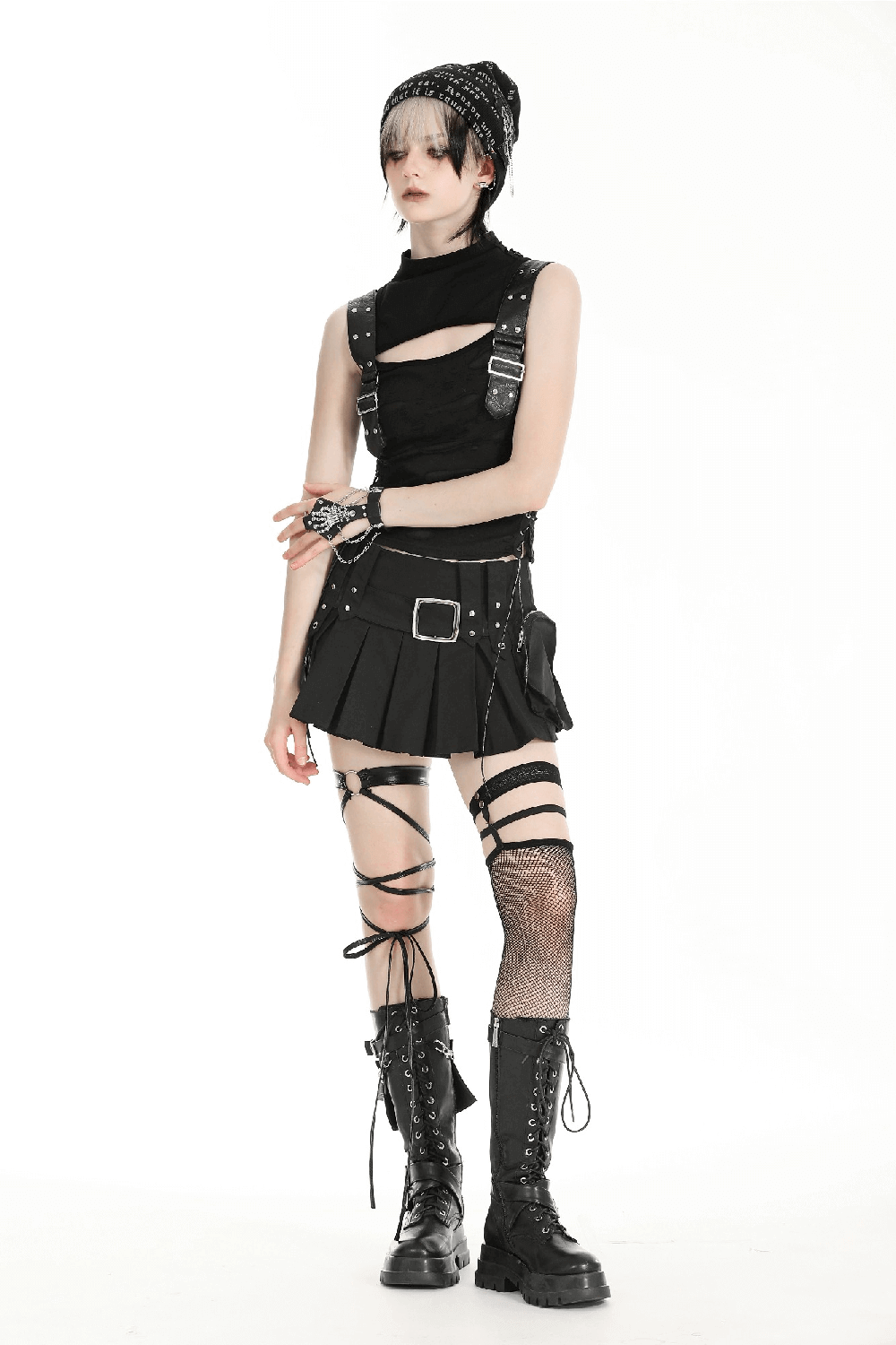 Gothic punk model in a sleeveless ripped top with buckle straps, black skirt, and lace-up boots, embracing edgy alternative fashion.