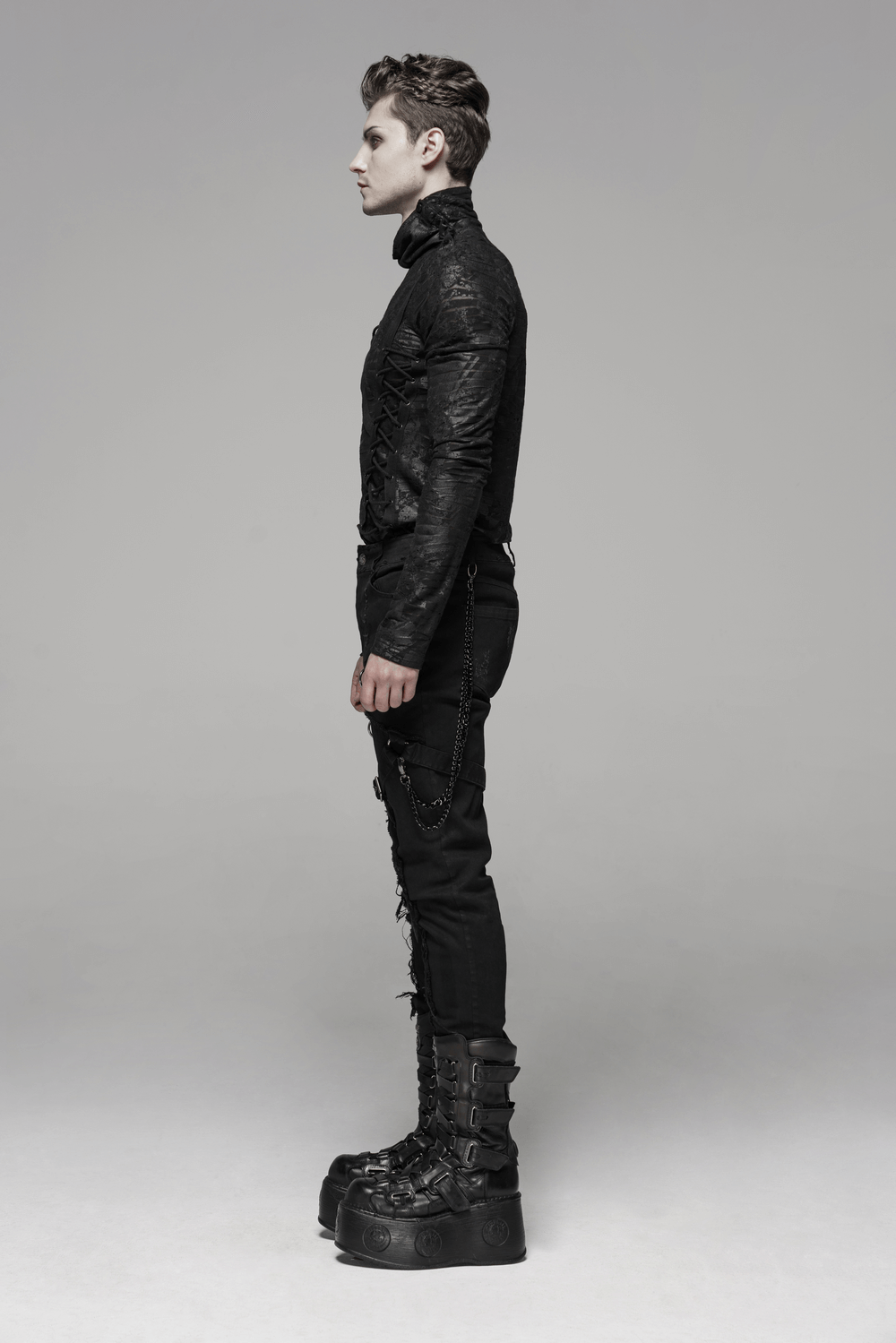 Edgy model in Gothic black cargo pants with chains and high platform boots, showcasing punk fashion style.