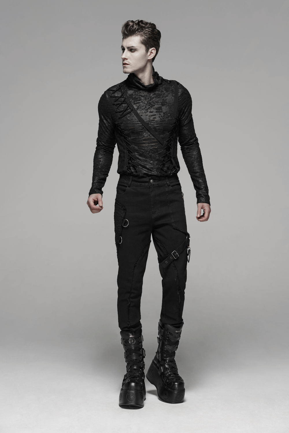 Gothic punk-style model in edgy black cargo pants with chain accents and stylish black top, showcasing rebellious fashion.