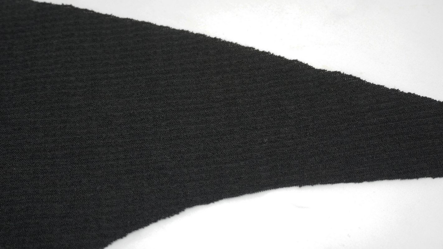 Close-up of a black fabric cutout from a gothic punk hoodie, showcasing texture and design elements.