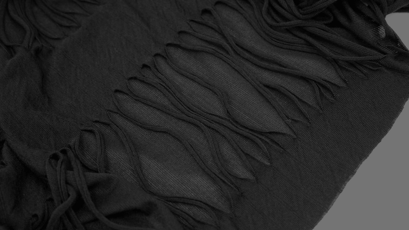 Close-up of black hoodie fabric with stylish cutouts and fringe detailing for gothic punk fashion.