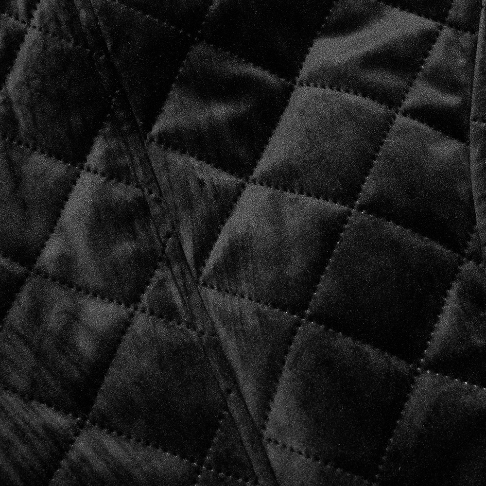 Close-up of quilted black velvet fabric, showcasing the luxurious texture of a Gothic waistcoat.