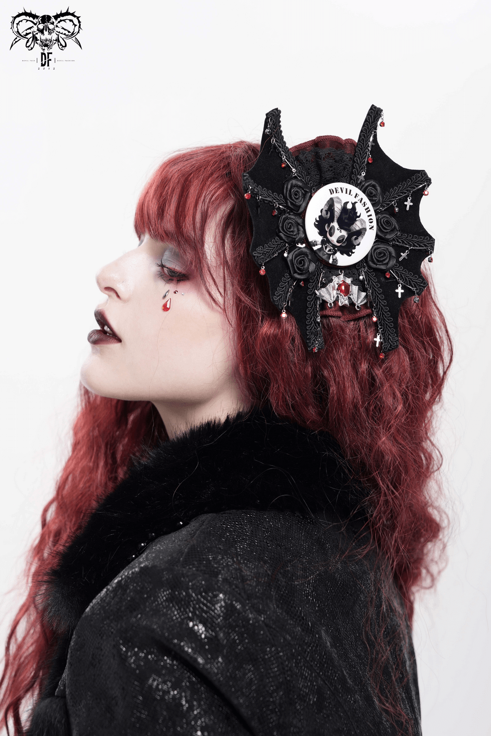 Gothic fashion headpiece with intricate black design, worn by a model with red hair and dramatic makeup.