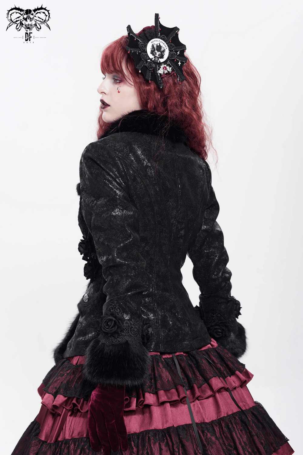 Gothic model with red hair in dark jacket and layered ruffled skirt, showcasing alternative fashion style.