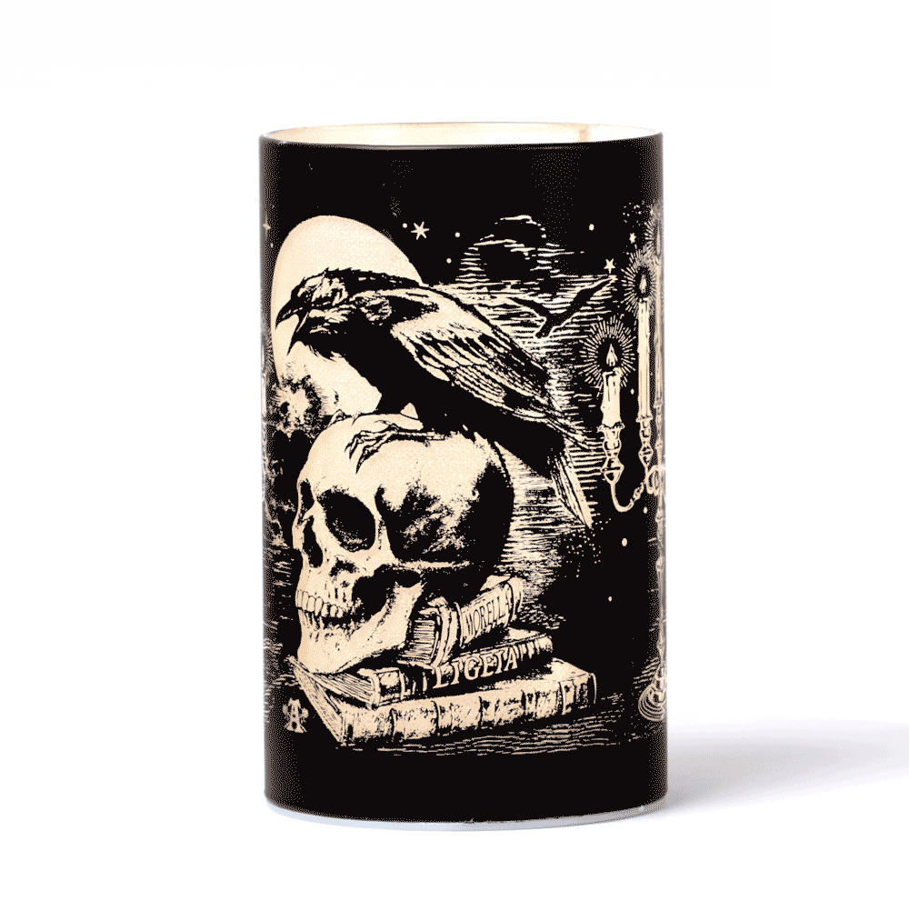 Gothic raven and skull patterned LED candle lantern with etched glass design, glowing eerily under the moon.