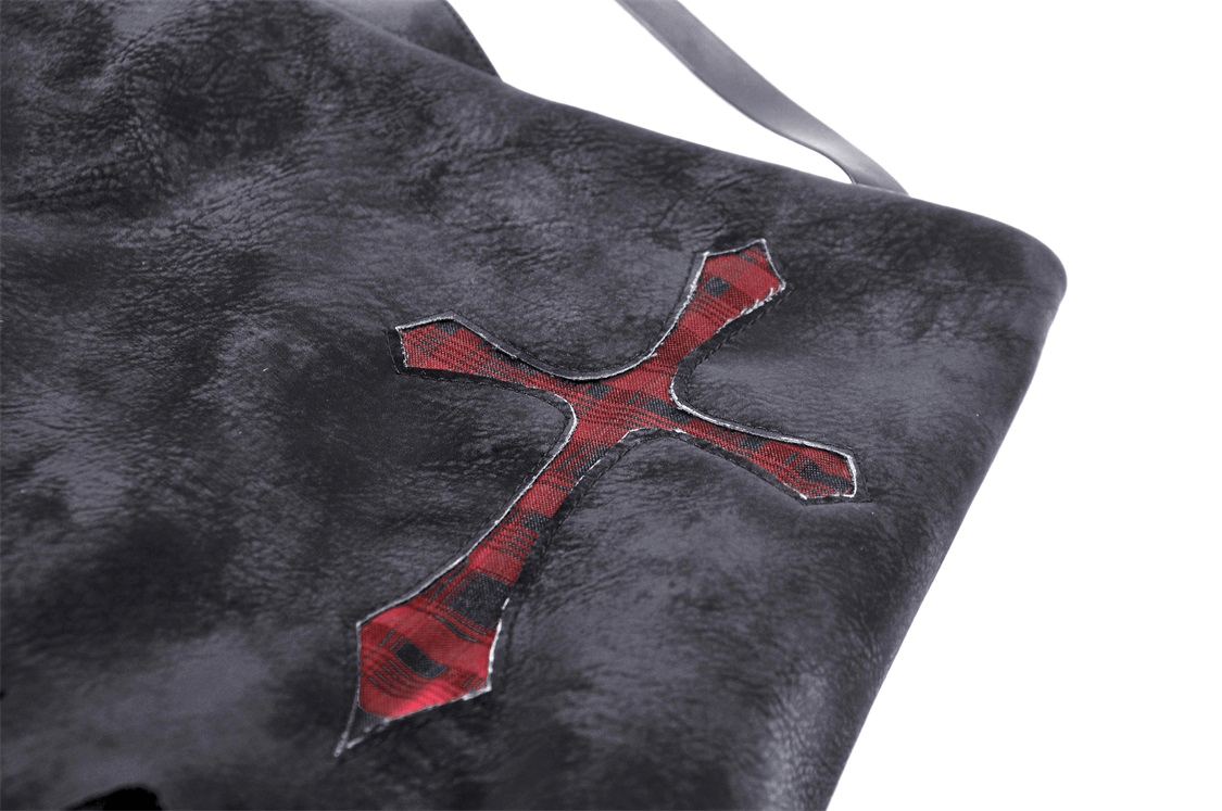Close-up of a gothic skirt featuring a red plaid cross detail on faux leather fabric.