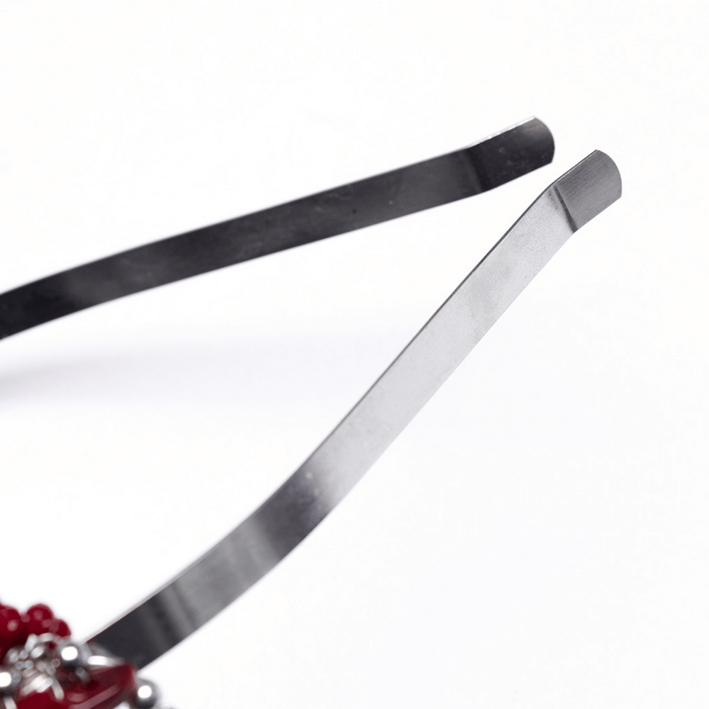 Close-up of the metal tips of a Gothic red crystal crown with silver cross tassels, showcasing detailed craftsmanship.