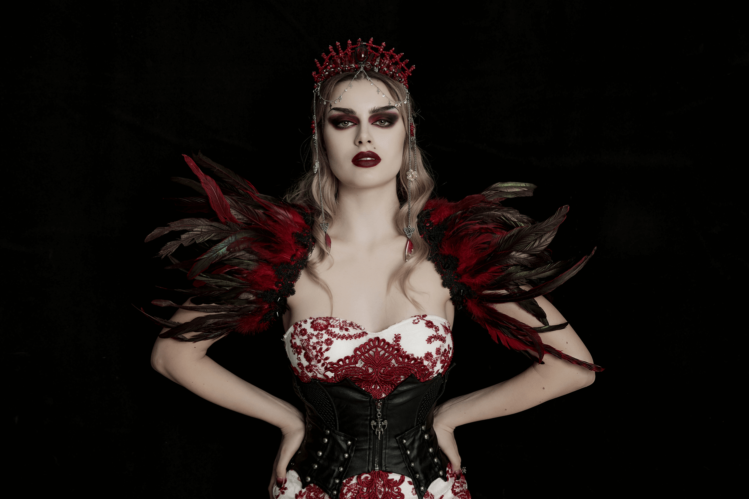 Gothic model wearing a stunning red crystal crown and dramatic feathered shoulder adornments.