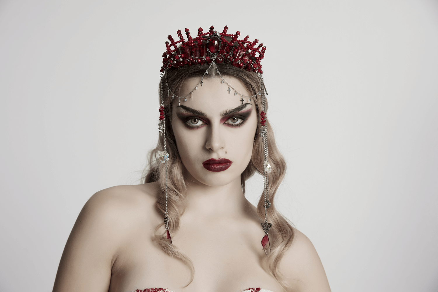 Gothic red crystal crown with silver cross tassels worn by a model, showcasing dark elegance and alternative fashion.