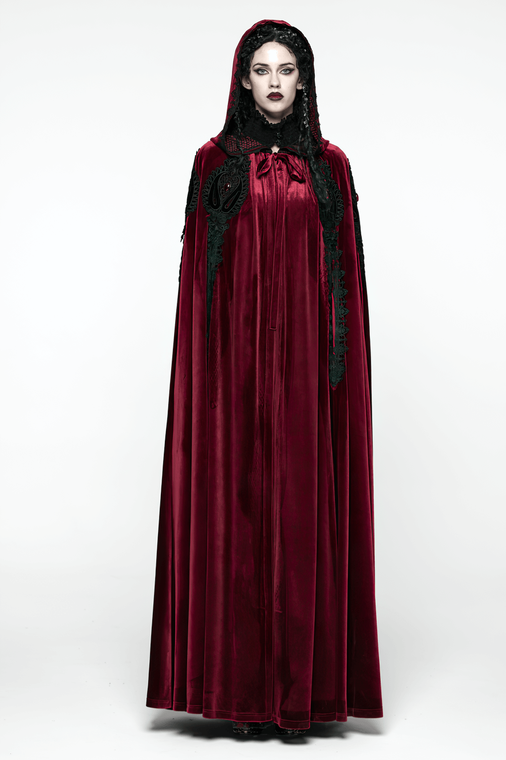 Gothic Red Velvet Hooded Cloak with Black Lace Trim modeled by a woman in a gothic inspired setting.