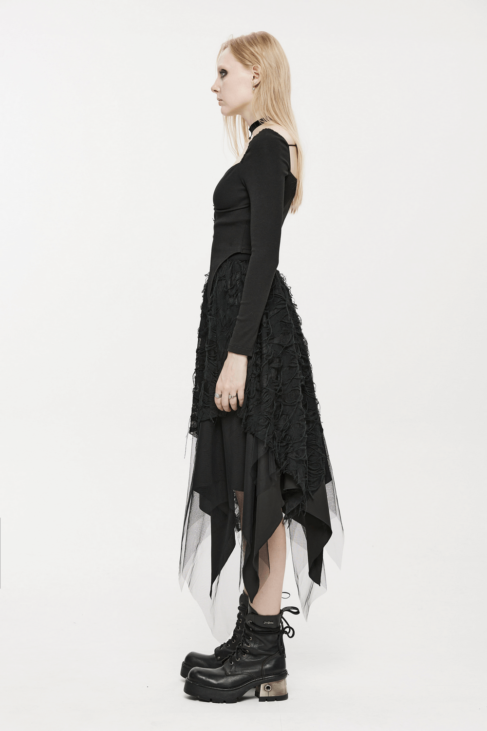 Side view of a model wearing a Gothic ripped butterfly asymmetrical mesh skirt with a stylish black top and chunky boots.
