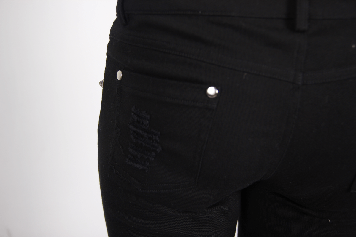 Close-up of women's gothic ripped black trousers featuring stylish torn inserts and decorative back pockets.