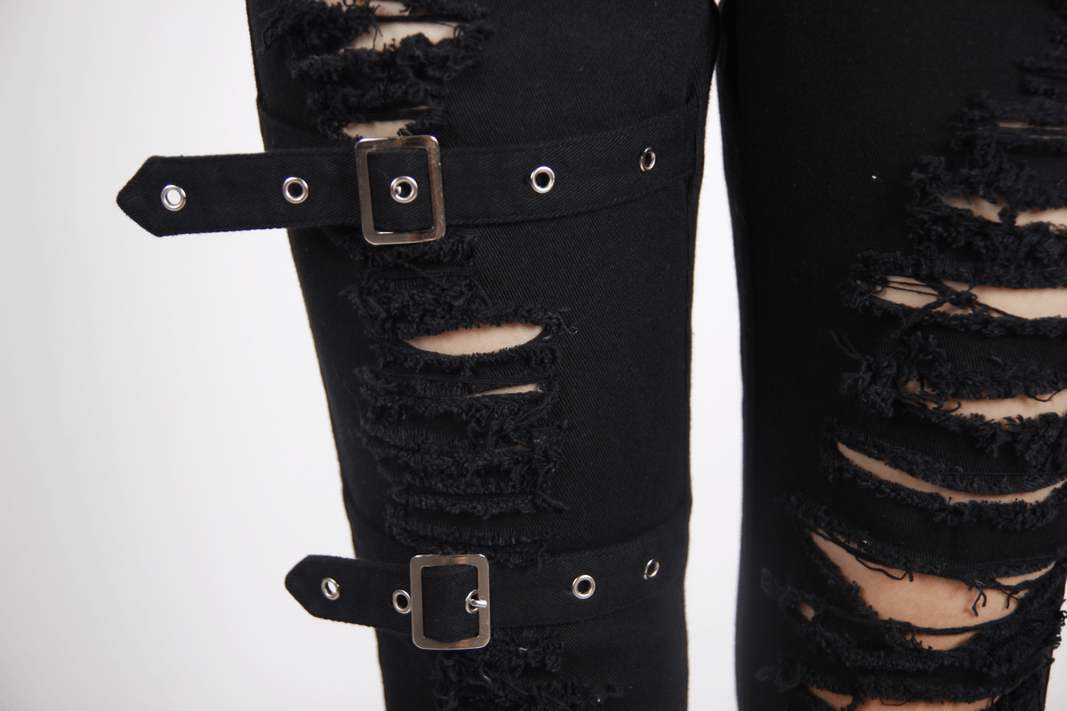 Close-up of gothic ripped pants with buckles, showcasing stylish torn details and a trendy black fabric.