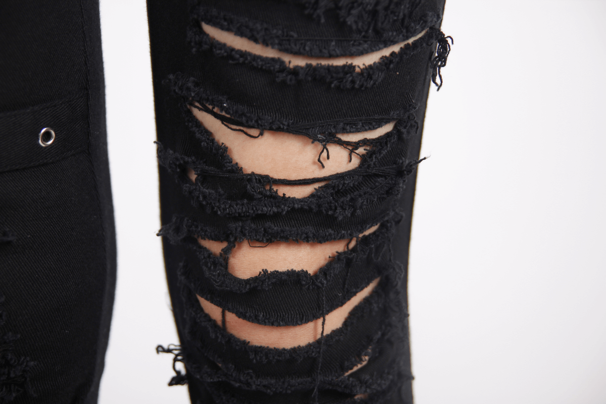 Close-up of gothic ripped black pants showcasing distressed fabric and stylish torn inserts.