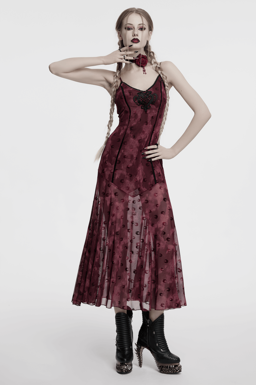 Gothic model wearing a vintage rose-patterned dress with lace and striking black boots, exuding dark elegance.