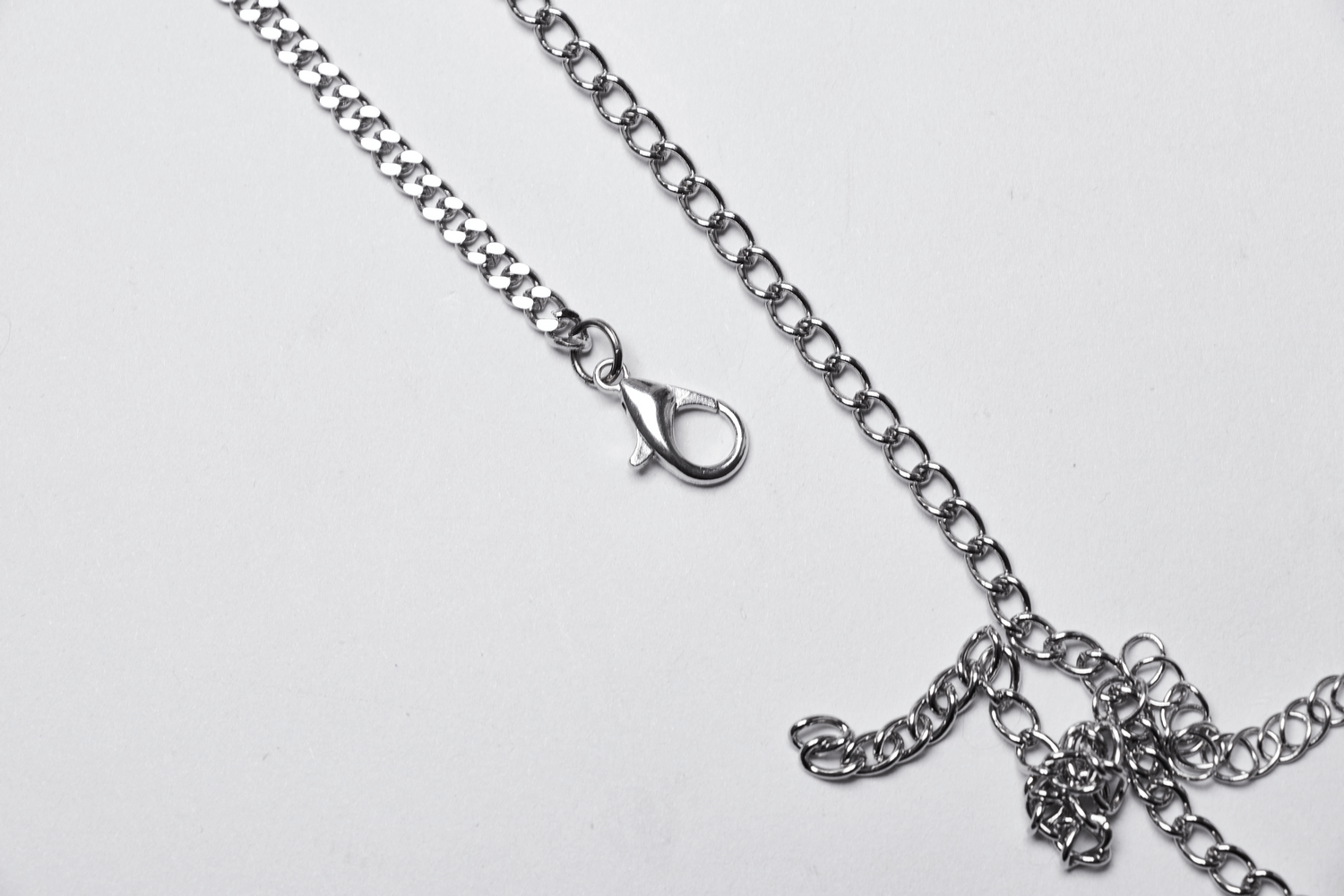 Gothic chain accessory with a clasp and rose charm detail on a white background.