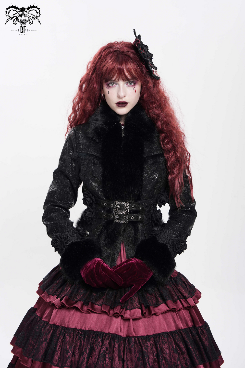 Gothic fashion model in layered skirt and stylish jacket with dramatic makeup and red hair, showcasing dark aesthetic.