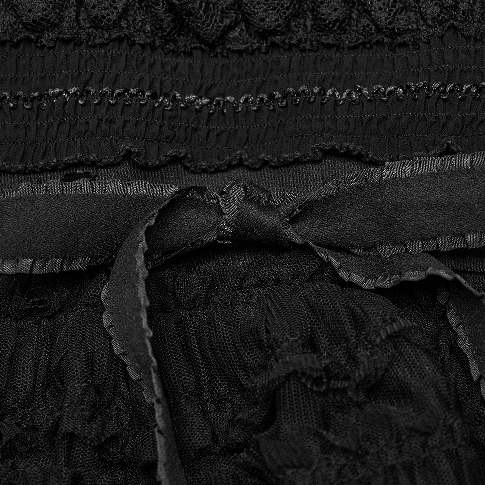 Close-up of gothic ruffled mesh leg warmers featuring black flare design and textured fabric detail.