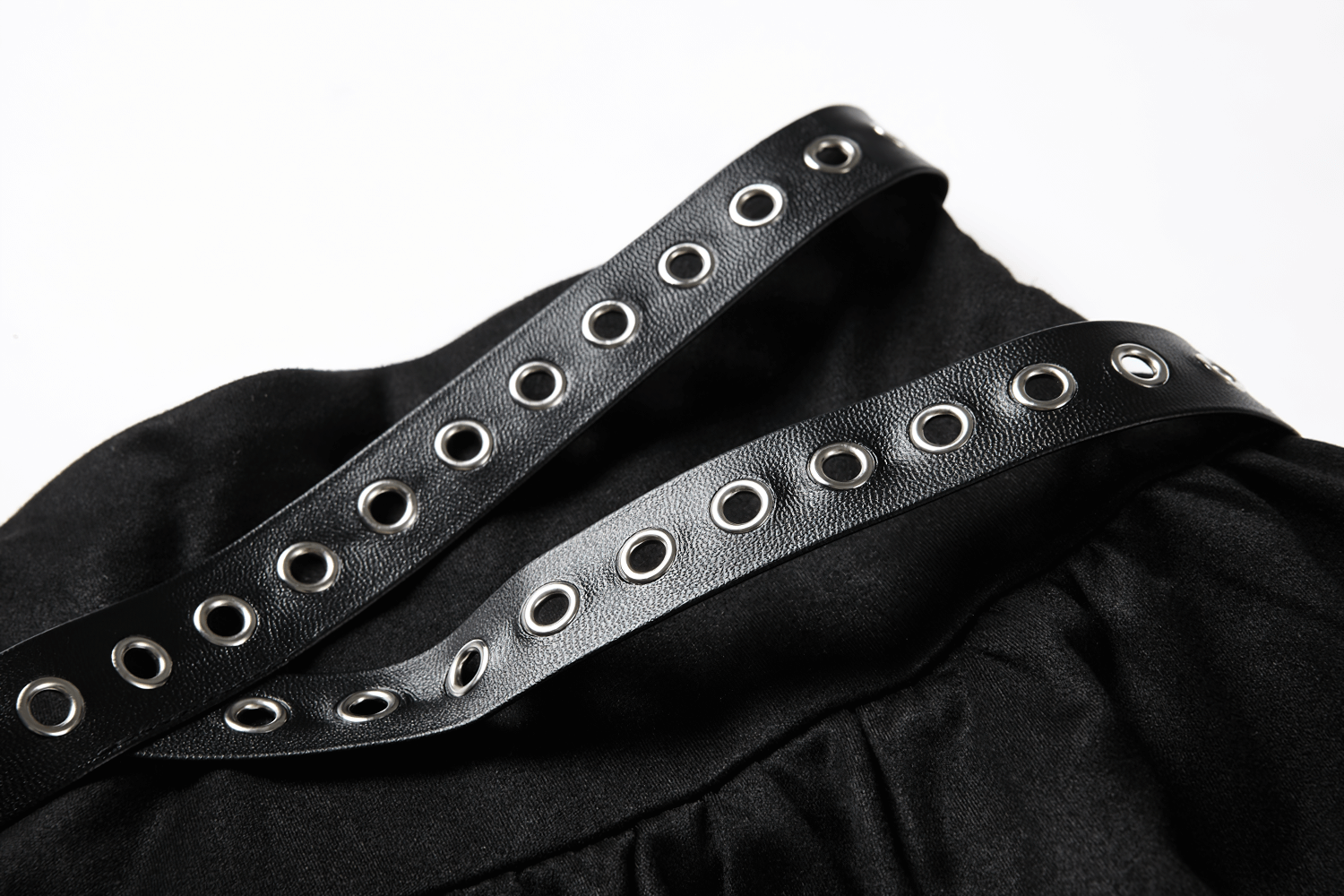 Close-up of ruffled black skirt with studded leather belt and metal grommets, showcasing gothic style details.