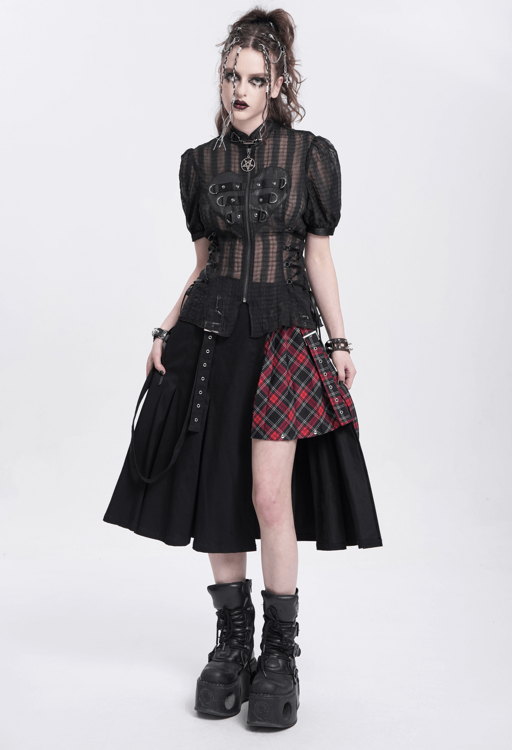 Gothic sheer black lace-up blouse with heart buckle, styled with plaid skirt and chunky boots, showcasing dark punk aesthetic.