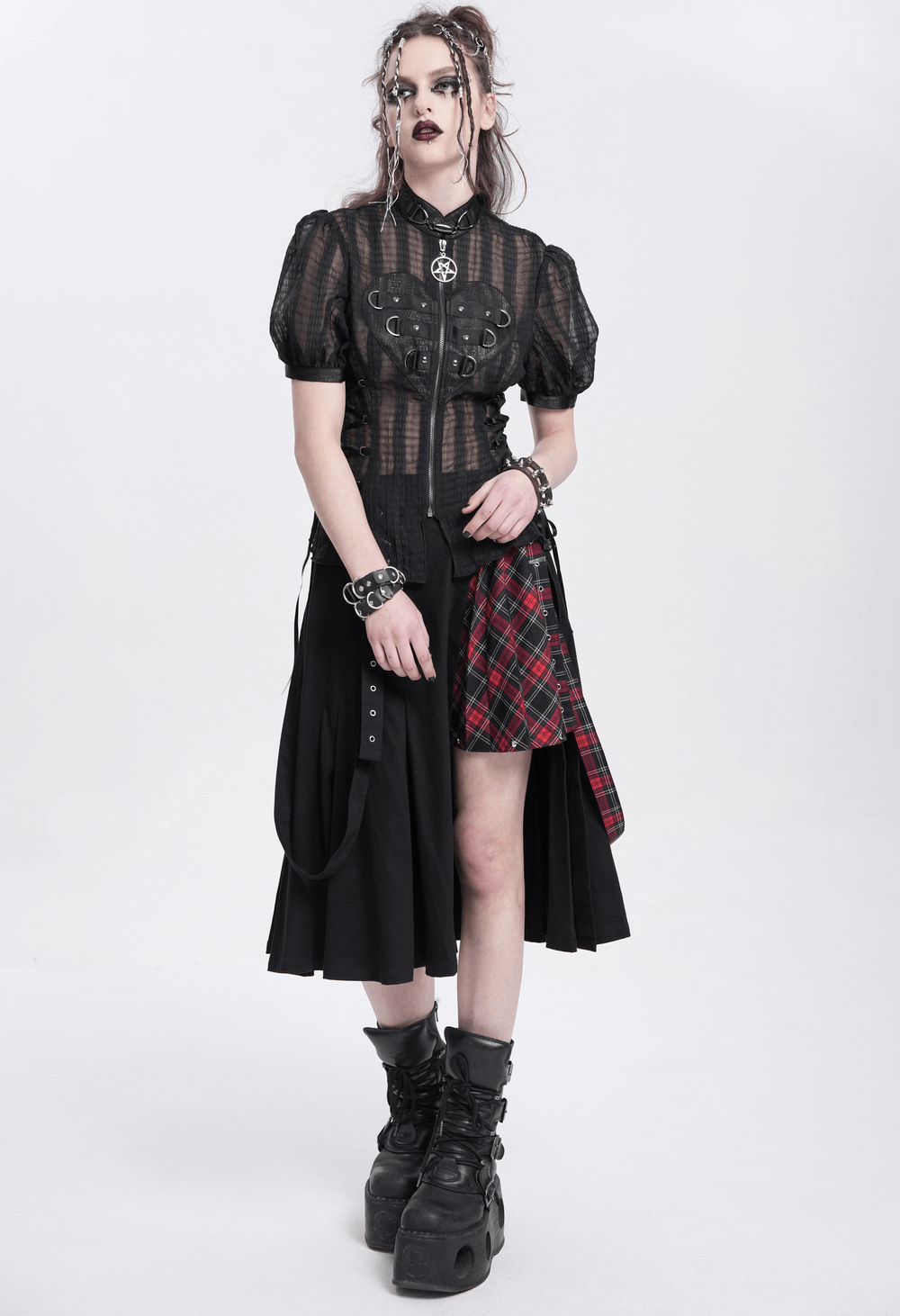 Gothic sheer black lace-up blouse with heart buckle, styled with plaid skirt and punk accessories, embodying dark romance.