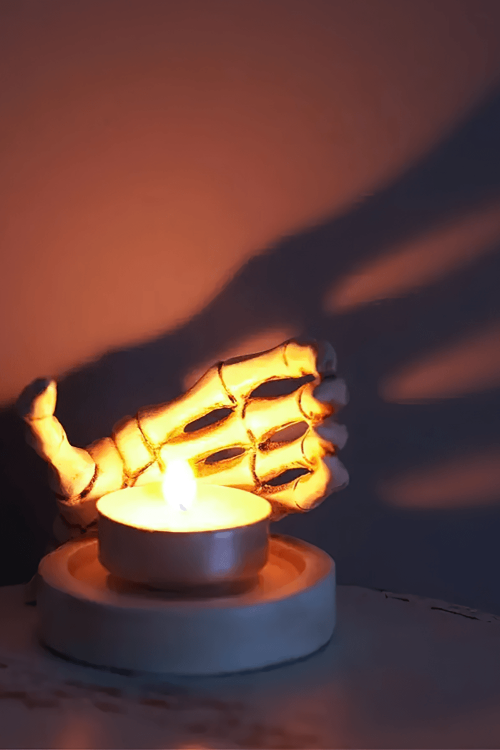 Gothic Skeletal Hand Candle Holder for Dark Decor casting shadows with a flickering candle on a moody surface.