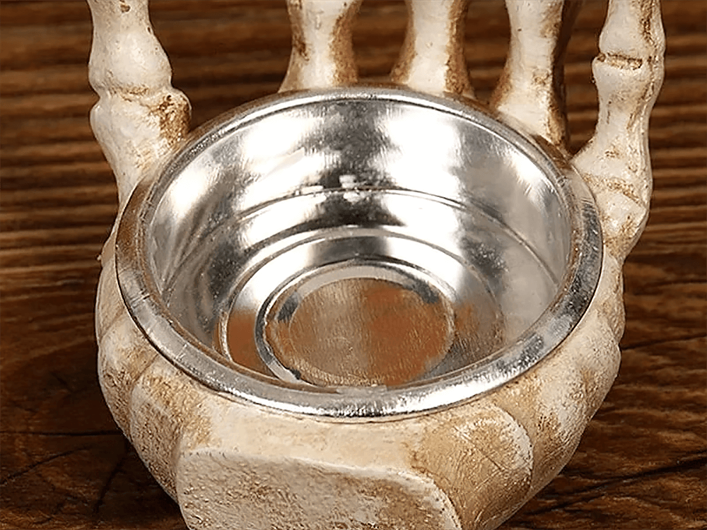 Gothic skeleton hand candle holder with metallic insert for Halloween decor and spooky ambiance.