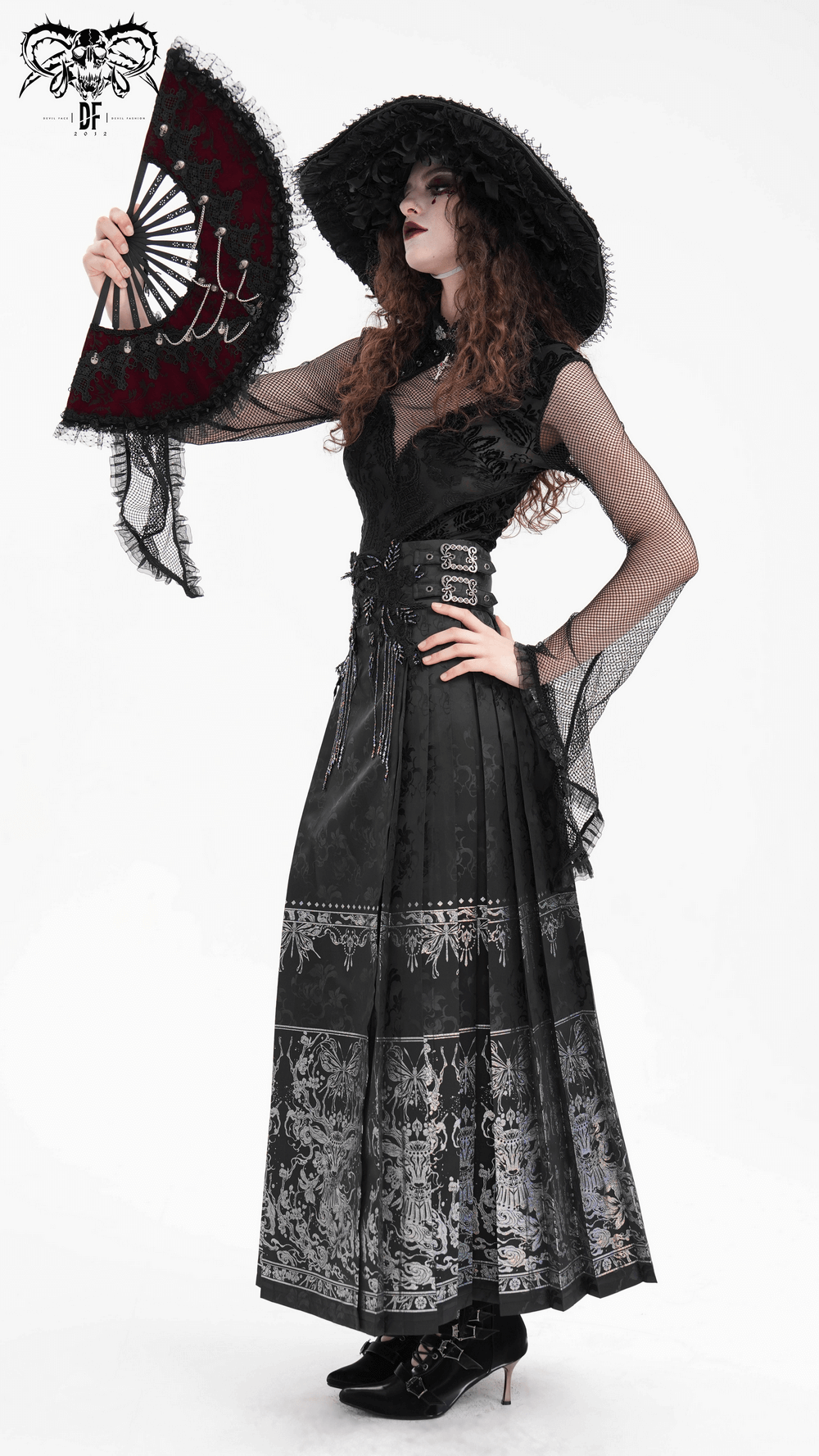 Elegant gothic fashion featuring a model in a black skirt with intricate embroidery and a stylish fan.