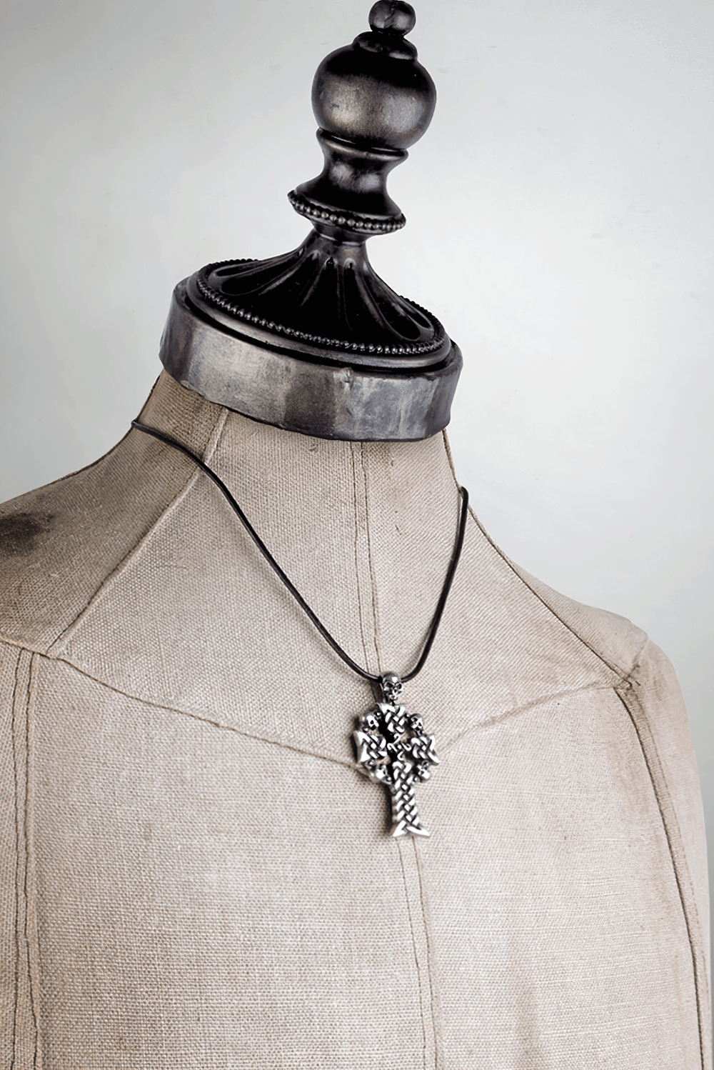 Gothic Skull Cross Pendant with Celtic Knot Design displayed on a vintage dress form.