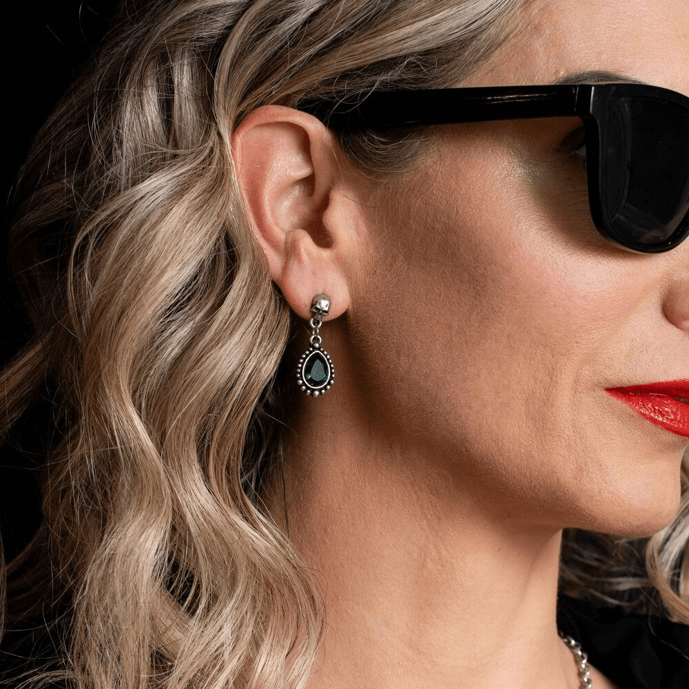 Gothic Skull Teardrop Green Crystal Dangle Earrings worn by a model with wavy hair and stylish sunglasses.