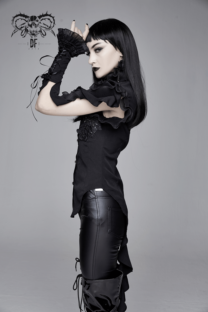Model showcasing a gothic sleeveless black blouse with floral embroidery and wavy ruffles, styled with edgy black pants.