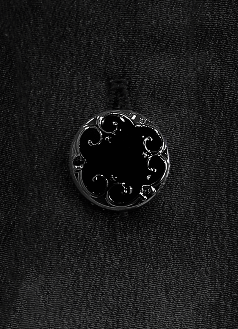 Close-up of gothic-style black button with intricate floral design on dark fabric, perfect for unique blouse details.