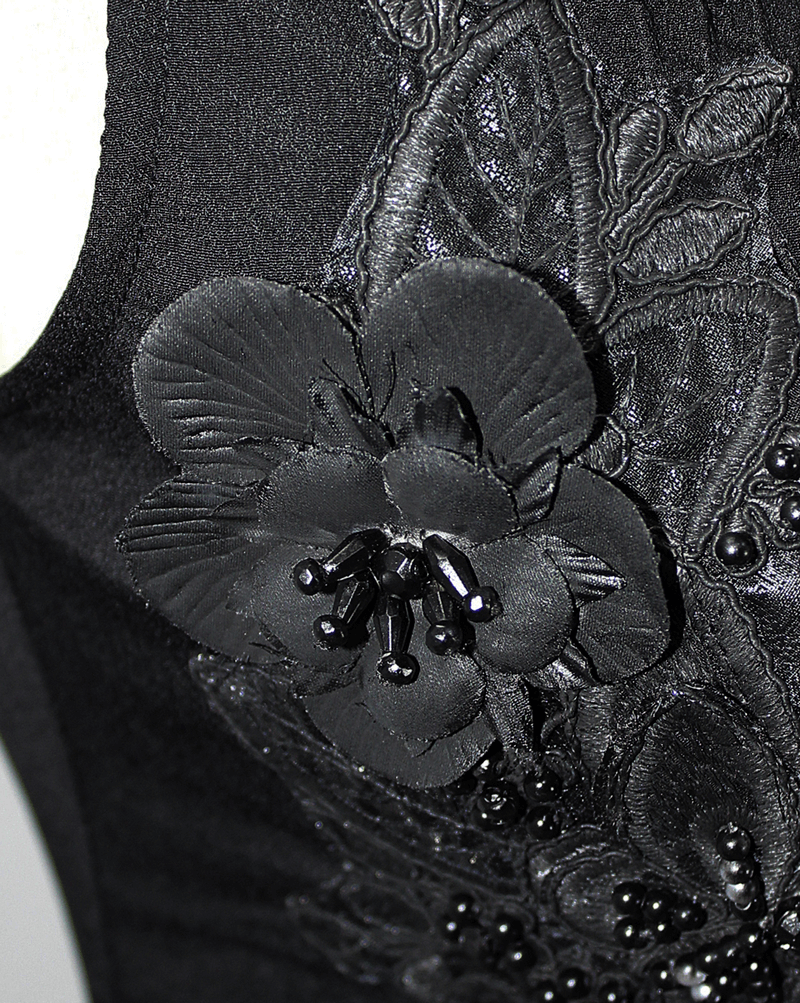 Close-up of black floral embroidery detail on a gothic sleeveless blouse, featuring lace and bead accents.