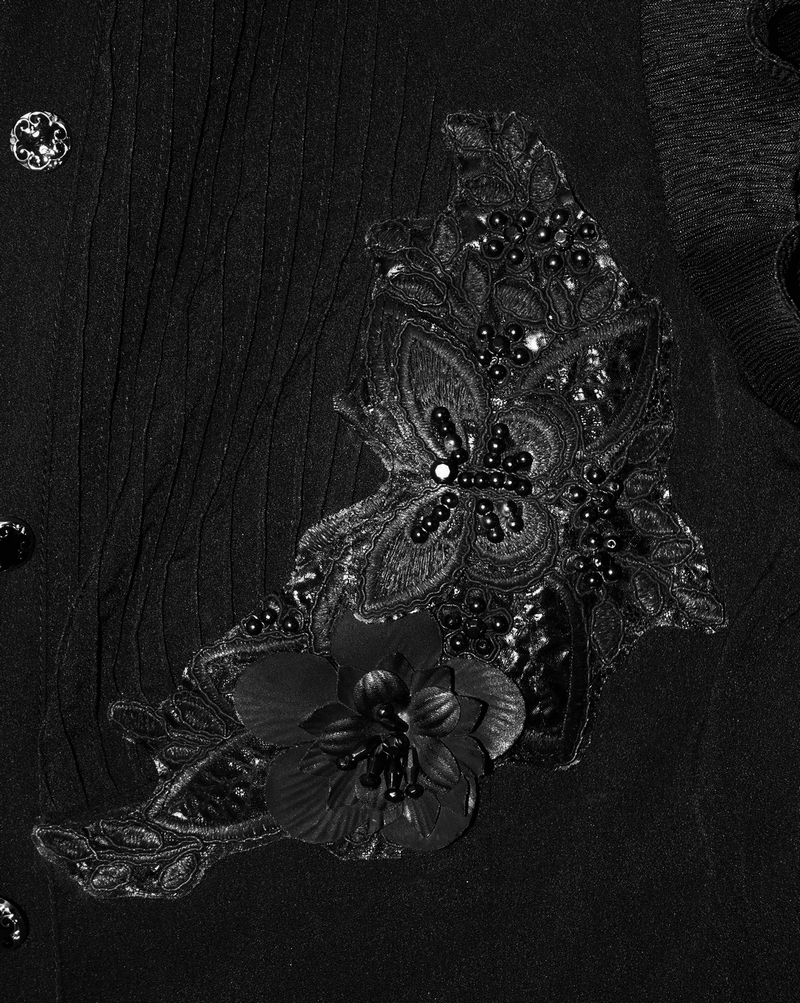 Close-up of gothic black blouse with floral embroidery and beaded details, showcasing elegant design and creative cut.