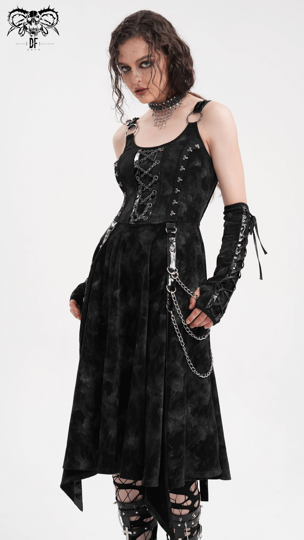 Woman in a Gothic slip dress with chains and gloves, featuring lace-up details and a high-low hem, exuding dark elegance.