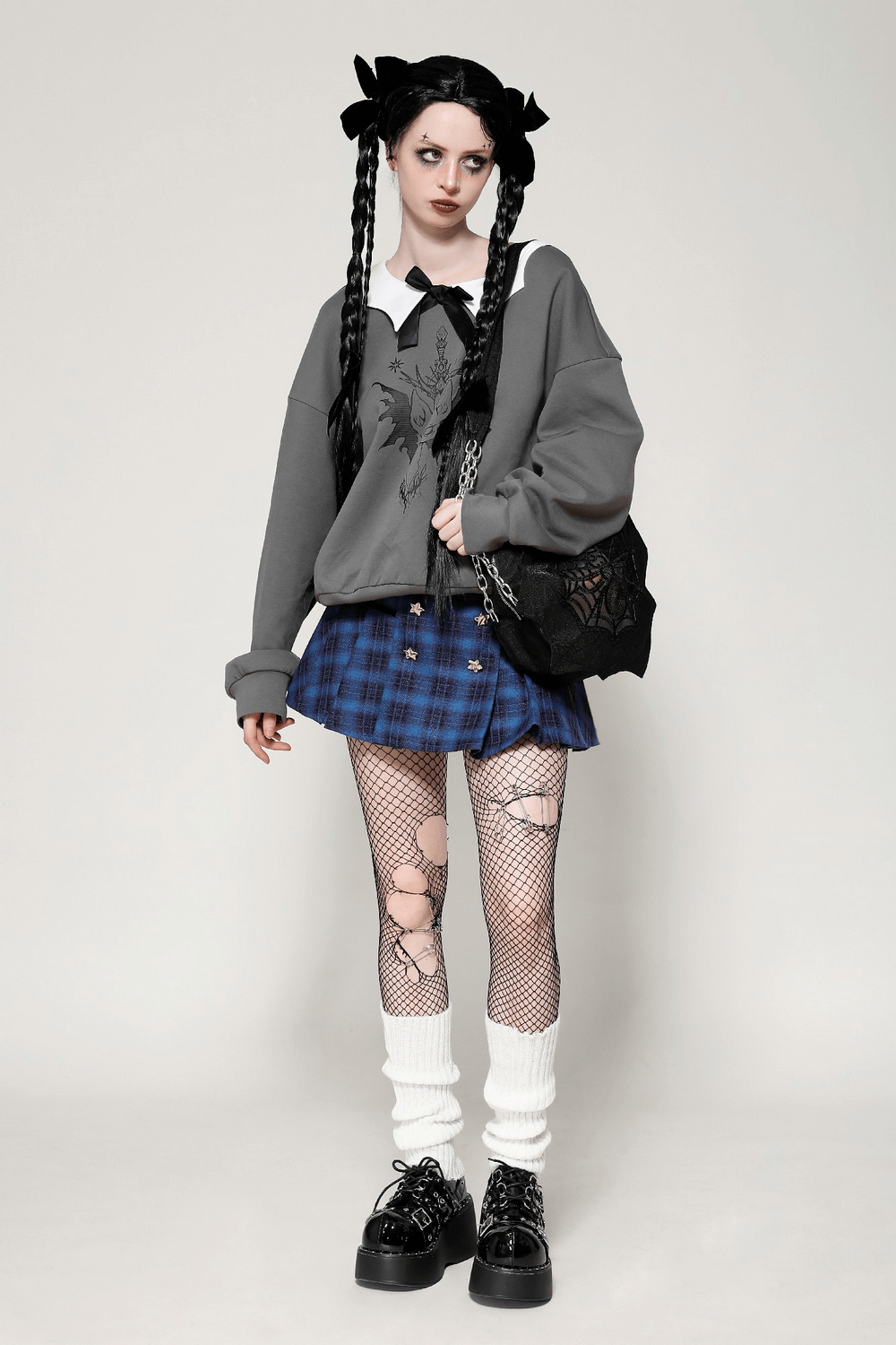 Stylish model with Gothic Spider Web Shoulder Bag and chain straps, wearing punk fashion with plaid skirt and fishnet tights.