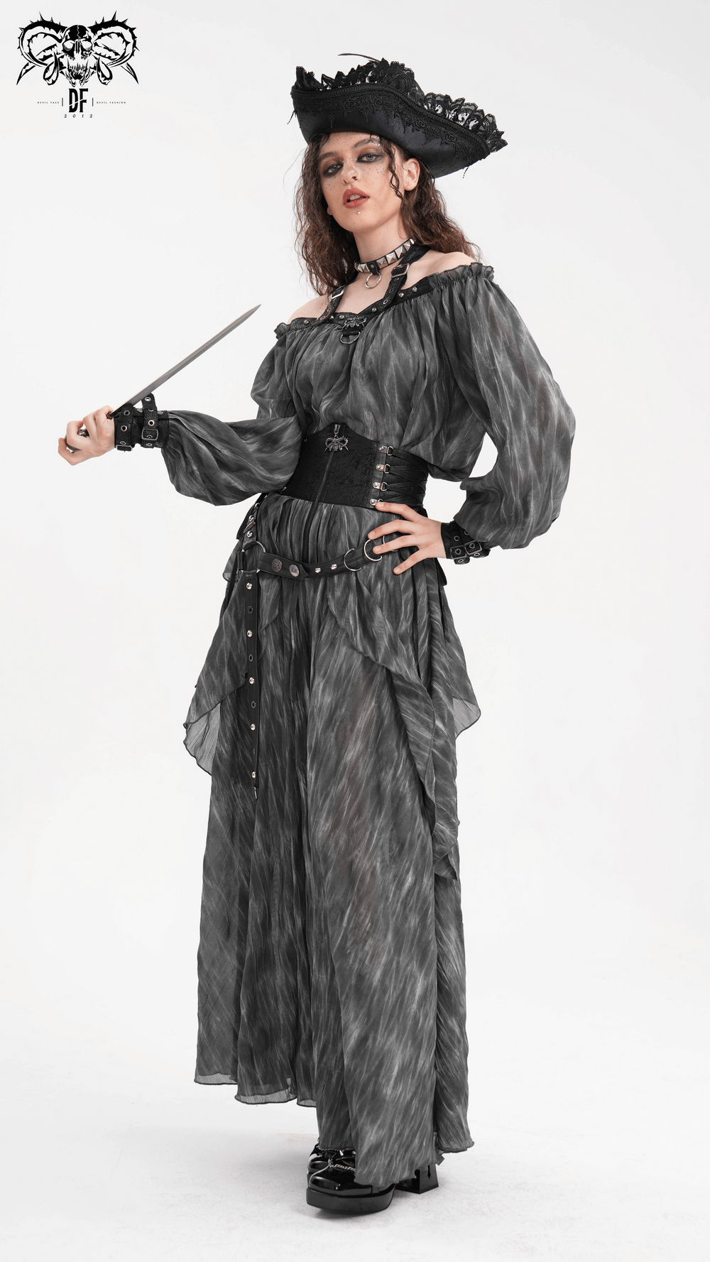 Gothic steampunk model in layered black dress with lace detailing, holding a dagger, showcasing alternative fashion.