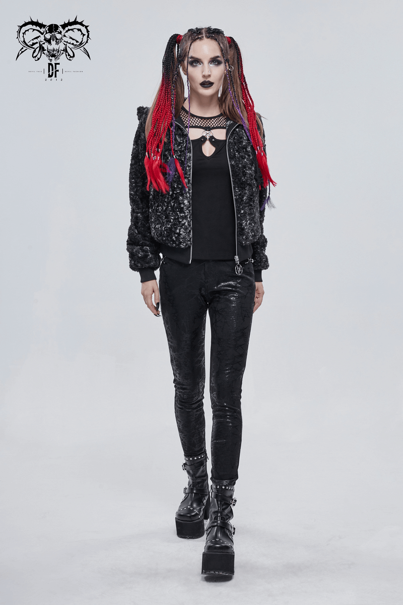 Gothic style woman in black strappy short jacket with hood, sporting red braided hair and platform boots.