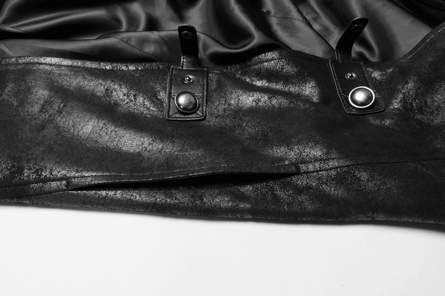 Close-up of stylish black leather buckle details on a gothic long cape for men.