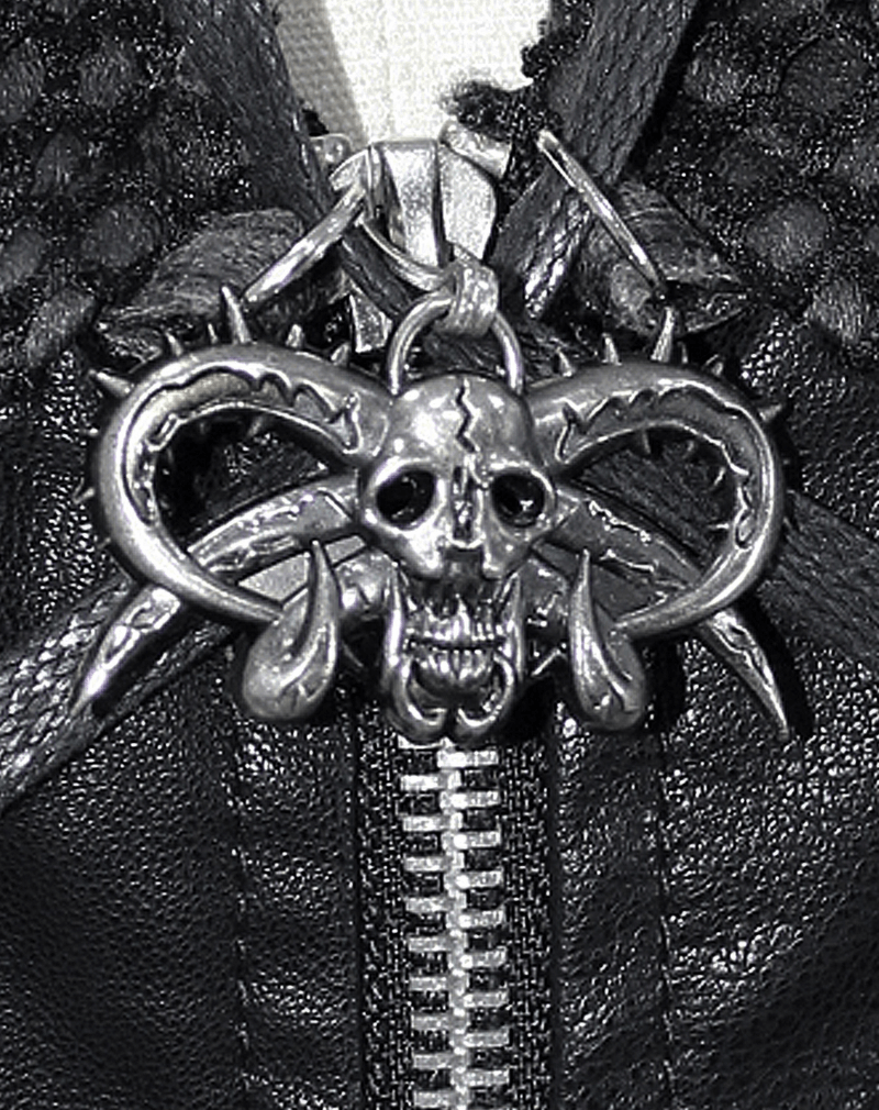 Close-up of a gothic skull zipper pull featuring horns and spikes on a stylish black coat.