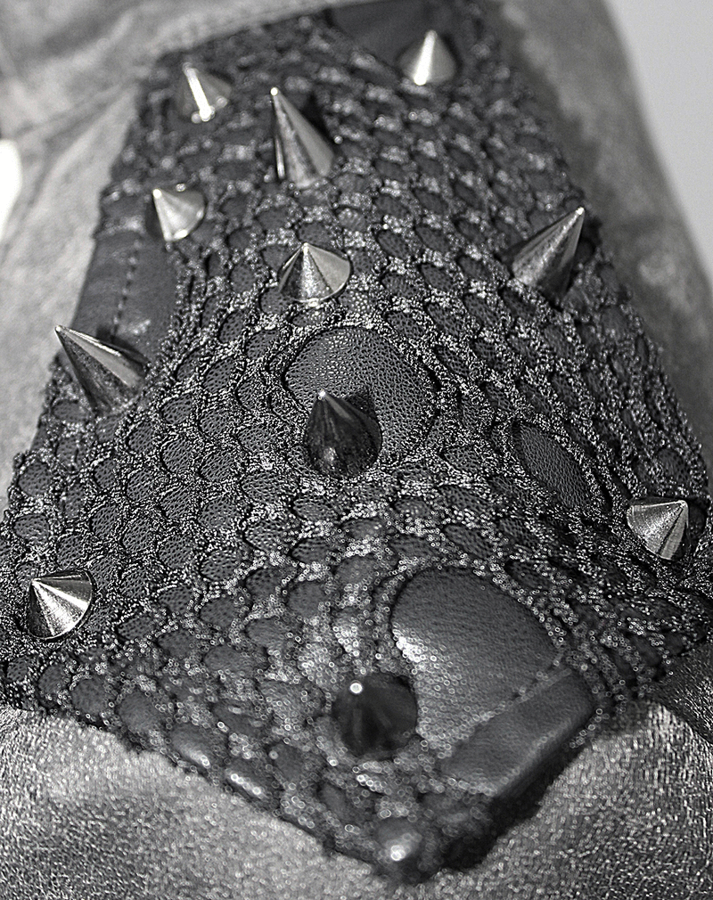 Close-up of gothic coat sleeve featuring black lace and shiny metal studs for a daring look.