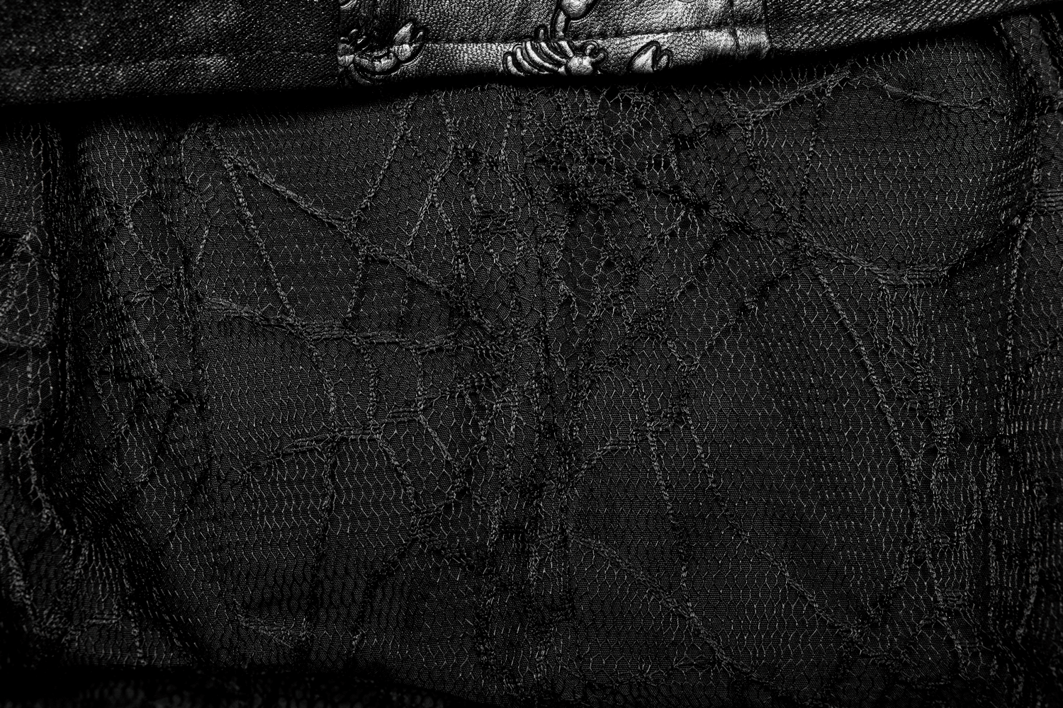 Close-up of intricate black fabric with spider web patterns, perfect for gothic fashion styles.