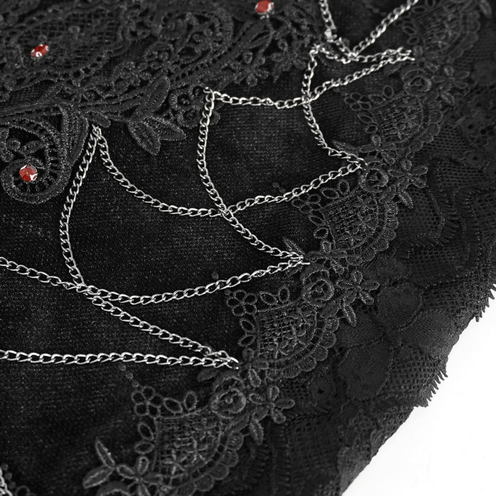 Close-up of black gothic skirt showcasing intricate lace, floral accents, and silver chain details for alt fashion elegance.