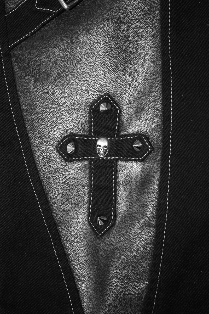 Close-up of a gothic black pant detail featuring a cross and skull embellishment, showcasing punk style fashion.