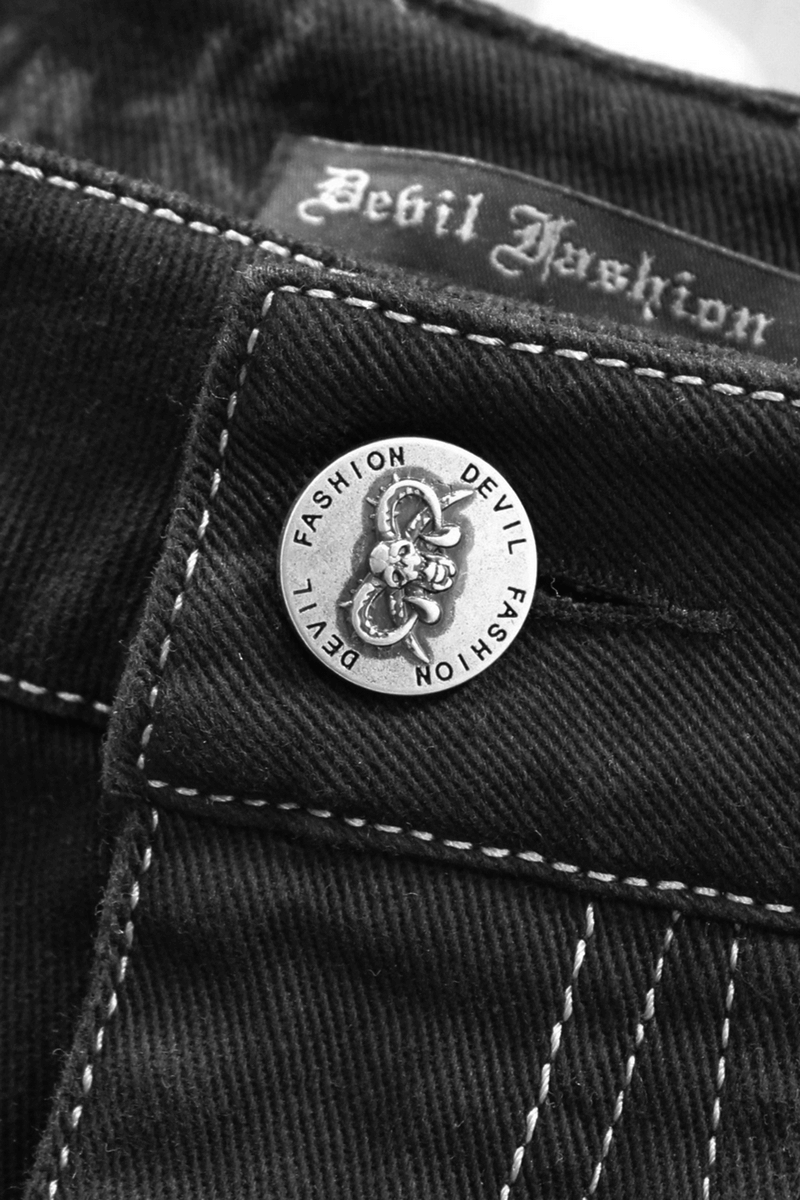 Close-up of Devil Fashion metal button on gothic-style black pants, highlighting trendy punk fashion details.